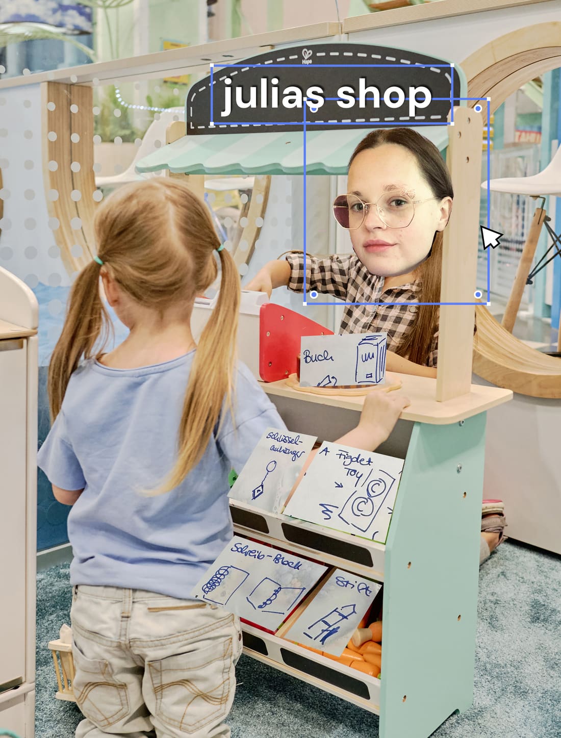 Meme-Mockup: Julias Gesicht auf einem Spielzeug-Kaufladen montiert, mit Zuschnitt-Werkzeug-Overlay wie in einem Design-Programm und handgeschriebenen Zetteln für Buch, Schlüsselanhänger, Fidget Toy, Schreibblock und Stift am Regal