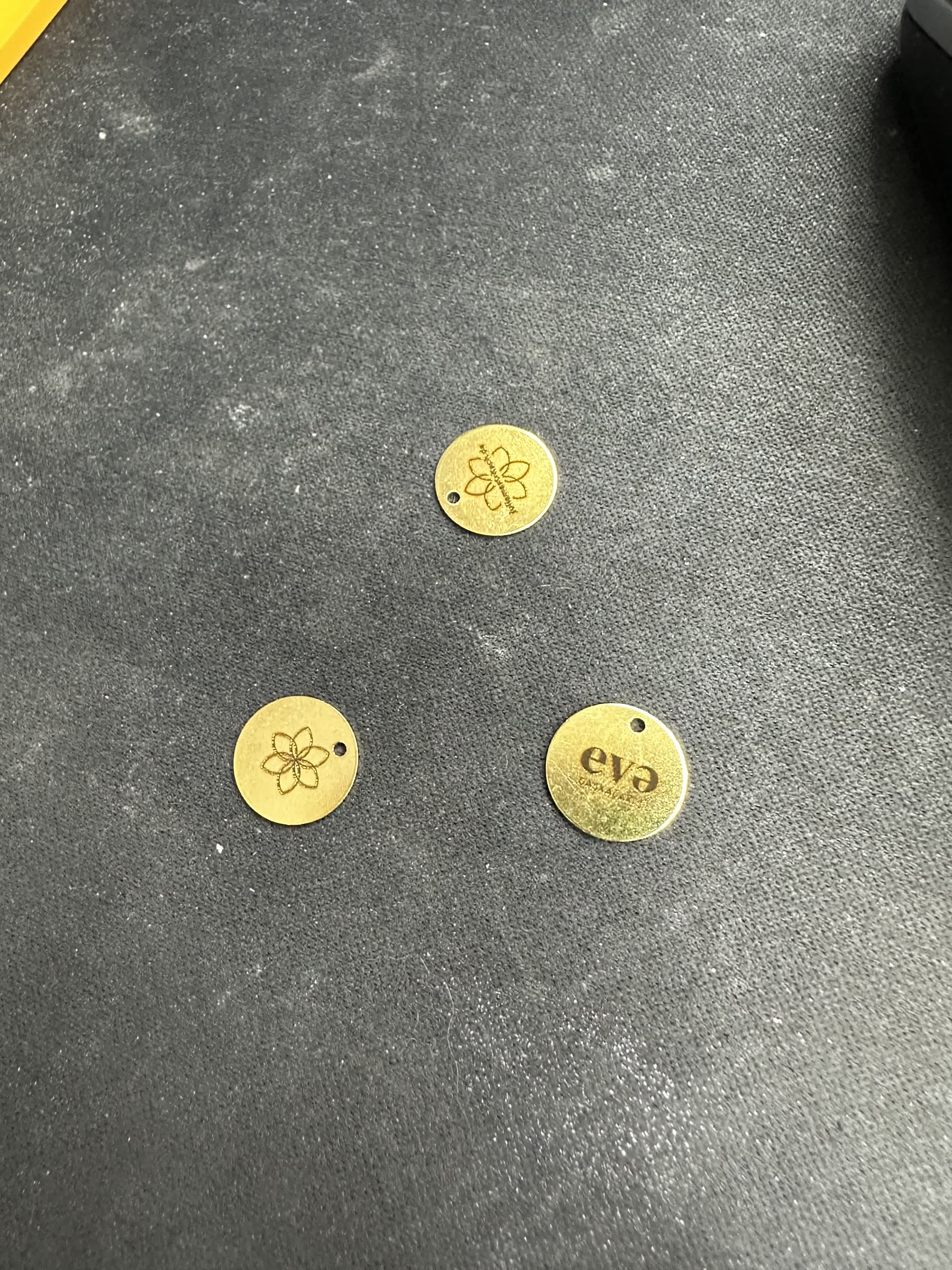 Nahaufnahme der frisch gravierten Messing-Plättchen mit Blumen-Logo