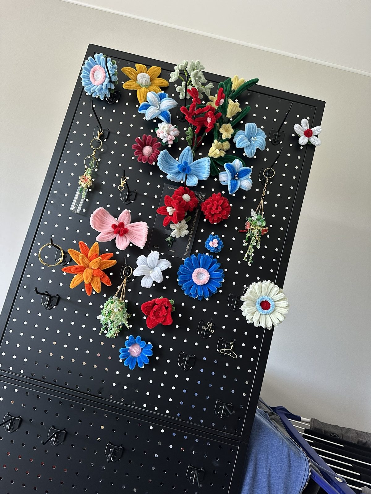 Experiment: viele bunte Pfeifenputzer-Blumen auf schwarzer Lochplatte
